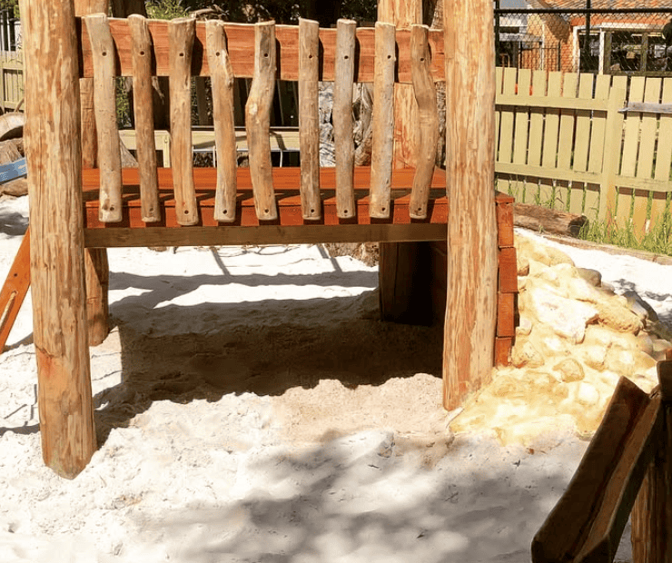 Climbing play structure with wooden beams and sand ground, outdoor children's playground equipment for active play and development.