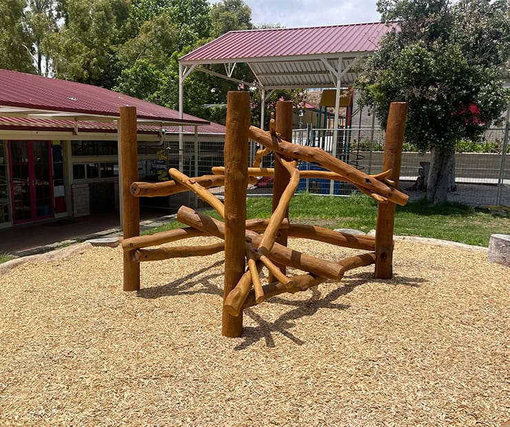 Natural wooden playground climbing structure in a safe outdoor kids' play area at DG Play, ideal for promoting outdoor recreation and physical activity for children.