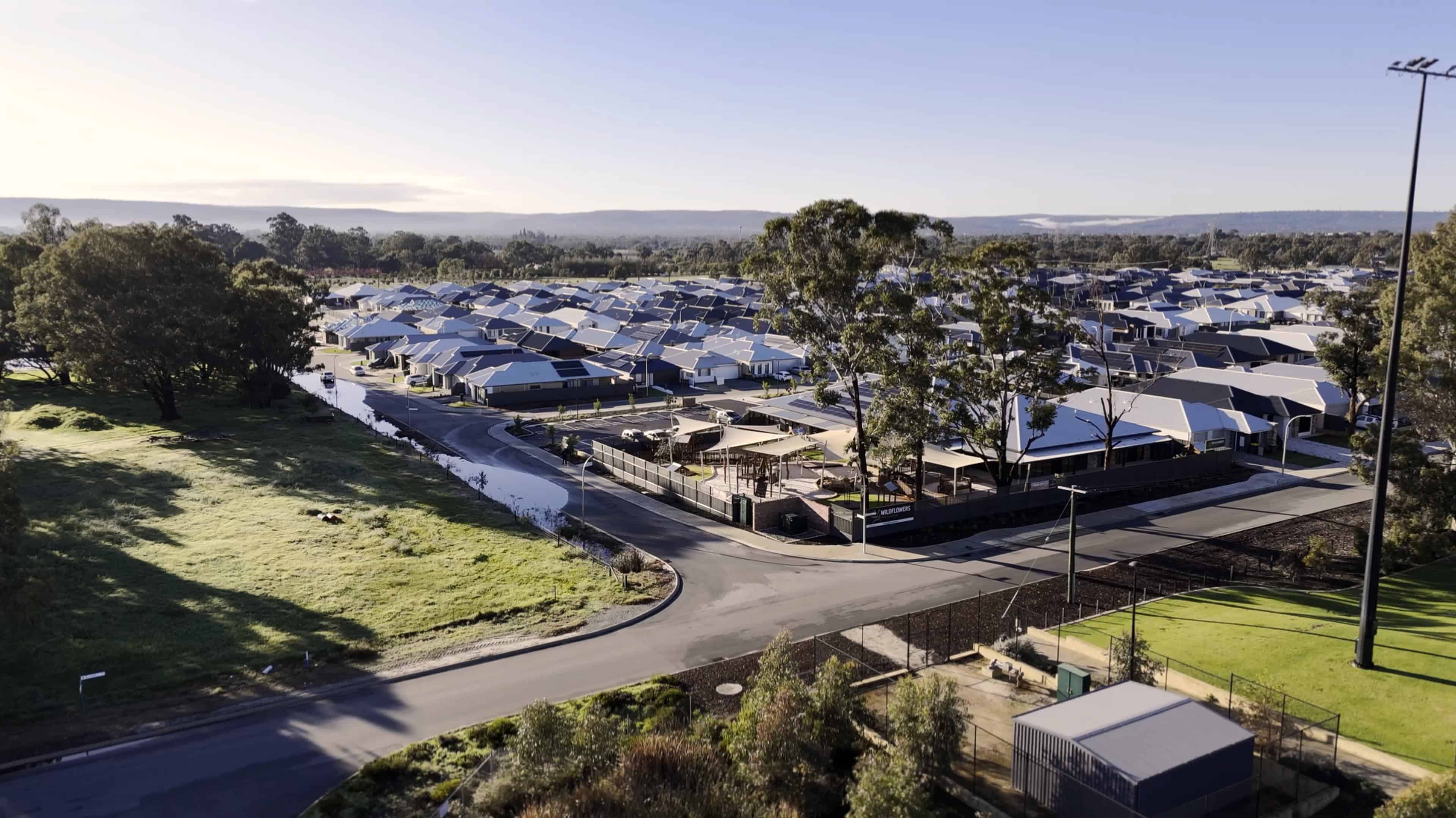 featured projects Modern residential neighborhood with solar-powered homes, lush green parks, and surrounding natural landscape, showcasing sustainable housing solutions and eco-friendly community living.
