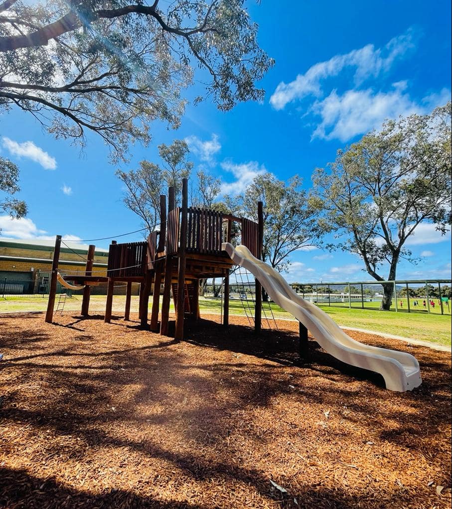 big john fort Wooden outdoor playground with slide under blue sky, perfect for kids at DG Play, outdoor recreation and children's play area, family friendly park, playground equipment, safe play space for children.