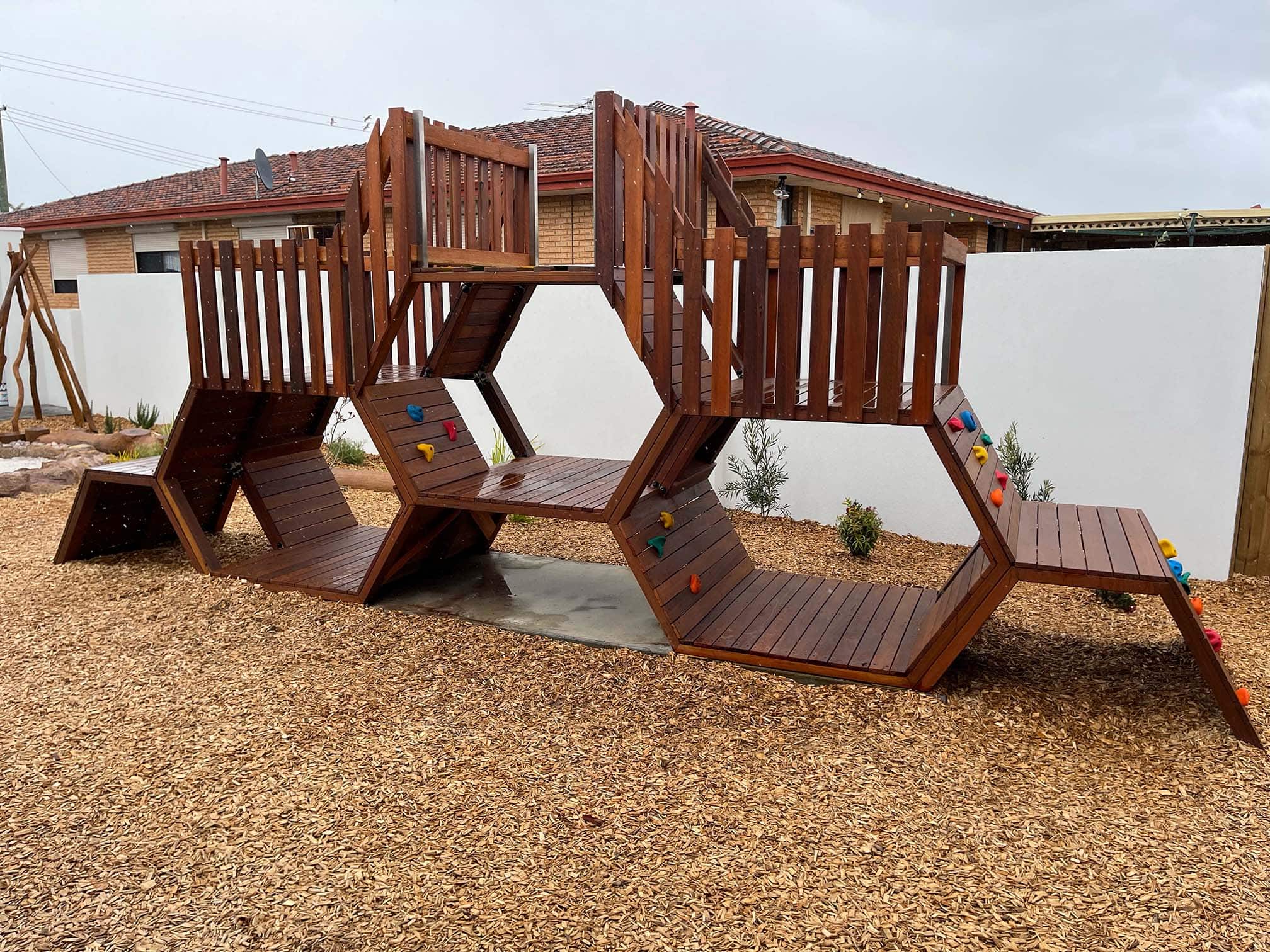 Bee Hive Climber wooden play structure for kids, featuring multiple levels, climbing walls, and slides, designed for outdoor play and active fun.