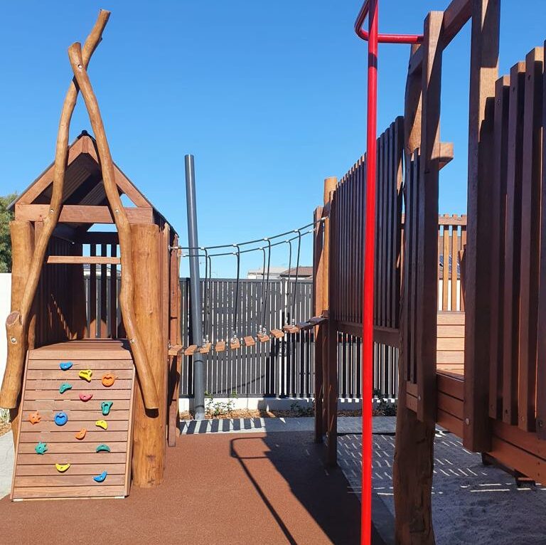 Outdoor playground with a wooden treehouse and climbing elements for children.