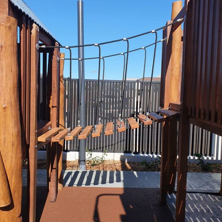 Playground rope bridge with wooden planks and safety ropes, designed for children to enjoy outdoor activities. Perfect for playgrounds, parks, and backyard play zones.