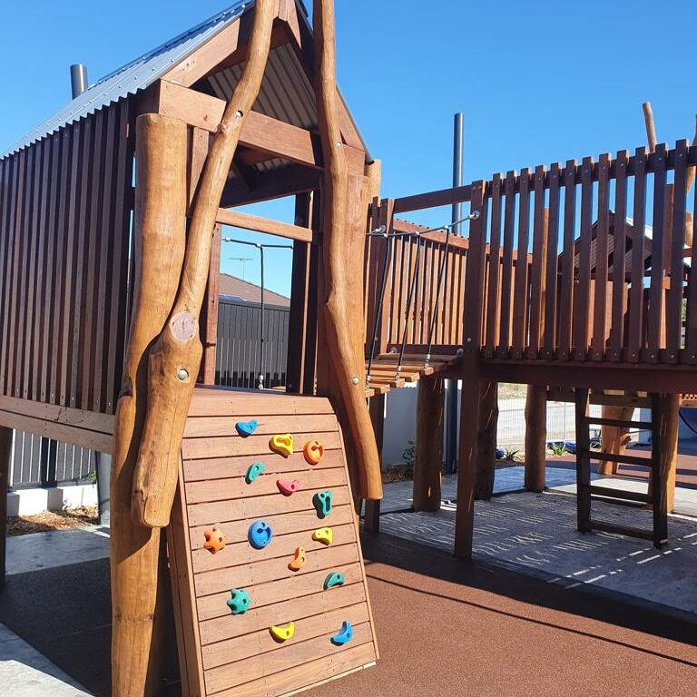 Wooden playground with climbing wall and slide, ideal for children's outdoor activities and play areas. Durable timber construction with safety features for kids' entertainment.