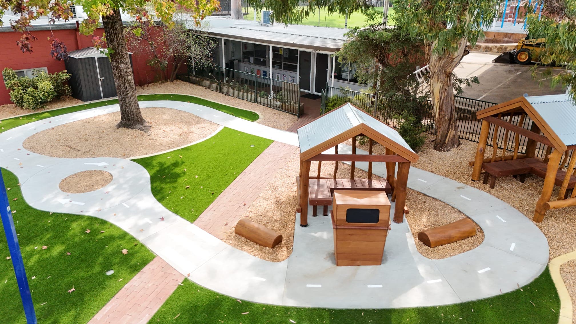 Outdoor children's playground featuring wooden playhouses, green grass, and paved pathways at DG Play. Perfect for kids' outdoor activities and family fun.